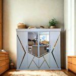 Modern white almirah with geometric gold accents and mirrored doors, placed in a cozy bedroom with wooden furniture and decor.