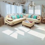 “Modern modular corner sofa set in a bright living room with beige upholstery, colorful floral and teal accent pillows, matching ottoman and natural sunlight streaming through large windows”