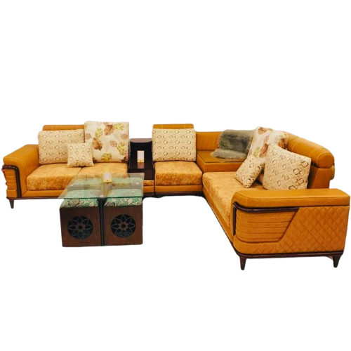 Modern L-shaped sectional corner sofa in mustard yellow fabric with printed and plain cushions, paired with glass-top wooden center tables.