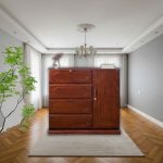 "Modern wooden wardrobe with four spacious drawers and side cabinet, placed on a beige rug in a stylish living room with wooden flooring and elegant décor."