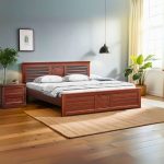 "Elegant wooden bed with decorative headboard and footboard, paired with matching bedside table, placed in a modern bedroom with wooden flooring and natural light."