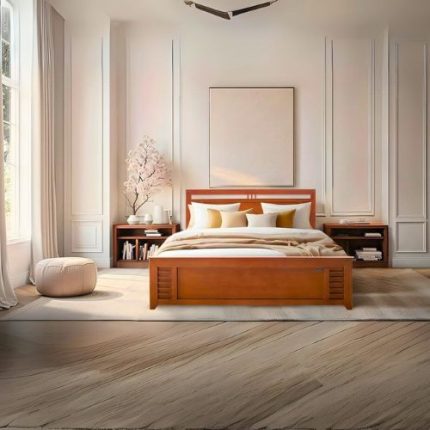 A warm, inviting bedroom featuring a wooden bed with a slatted headboard and footboard. The bed is dressed with white and gold pillows and a gold-colored blanket. On either side of the bed are matching wooden nightstands with built-in bookshelves. The room has light wood floors and a light-colored rug. A large window with sheer white curtains is on the left, and a small, white tree branch with pink flowers sits on one of the nightstands.