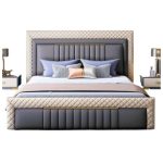 Elegant modern upholstered bed with beige padding and gold metal frame in a stylish bedroom with sunburst mirror, bedside lamp, and floor-to-ceiling curtains.